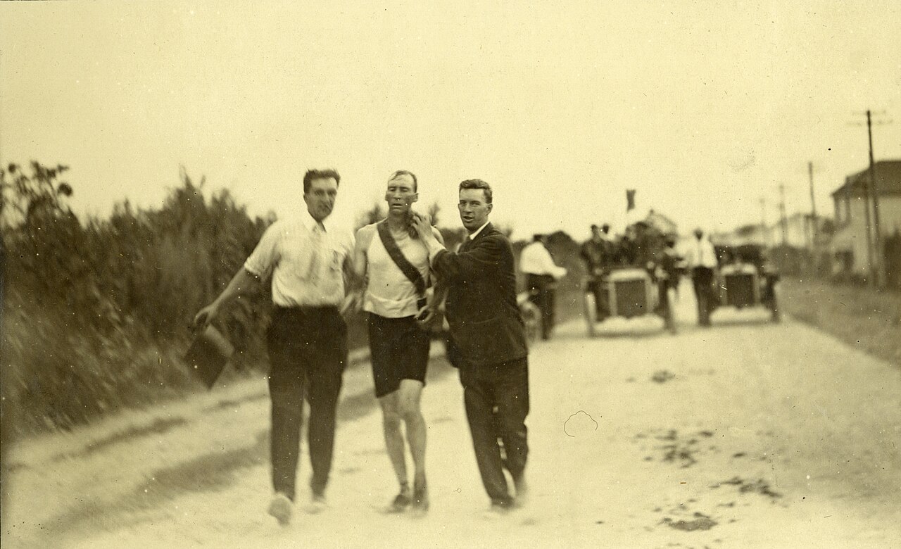 Thomas Hicks held up by two attendants on a dusty road during the 1904 Olympic marathon
