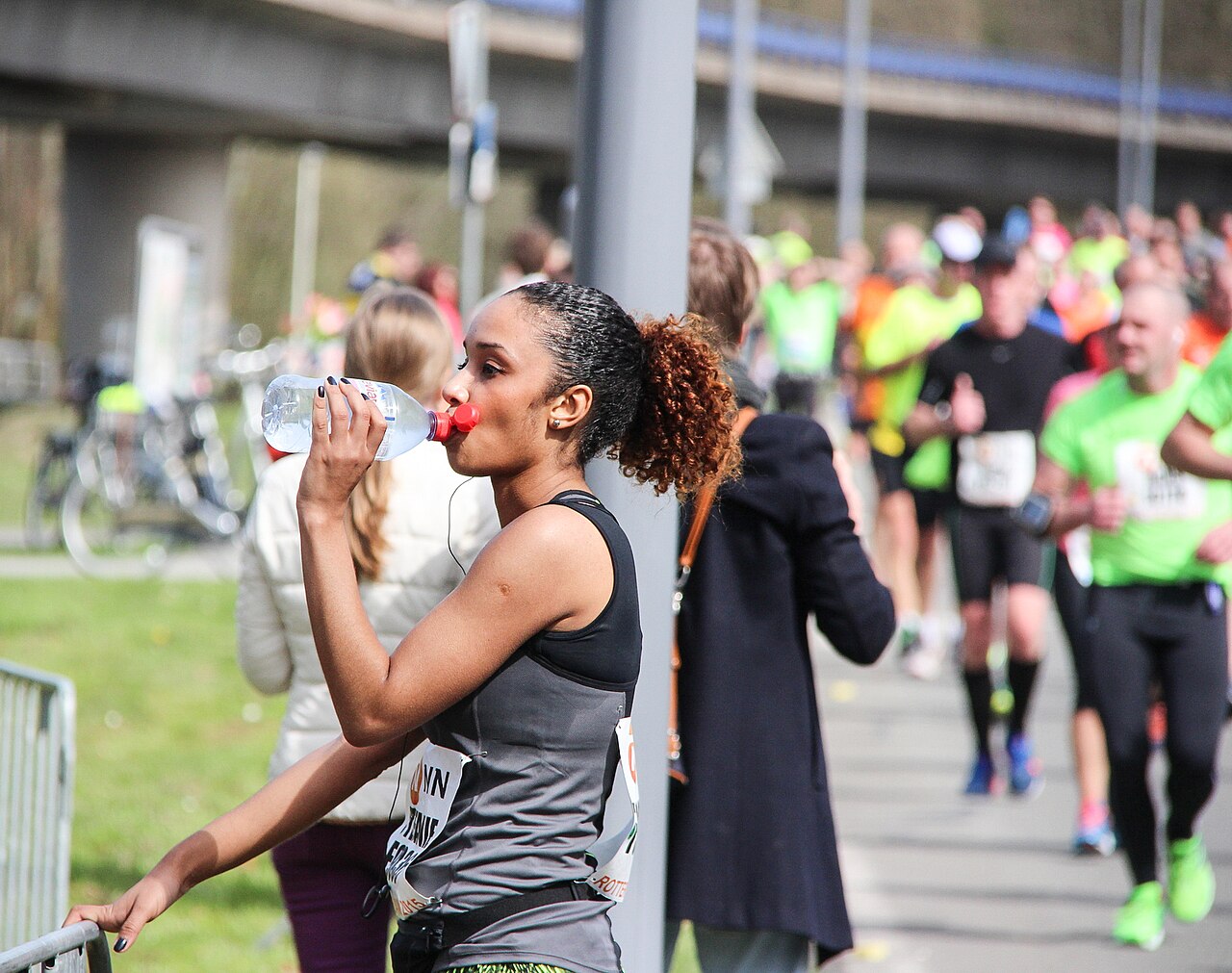 A runner stopped at the side of the course drinking from a water bottle during the Rotterdam Marathon